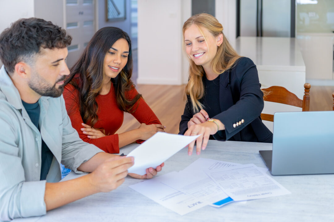 A Realtor Reviews Closing Documents With Her Homebuyers